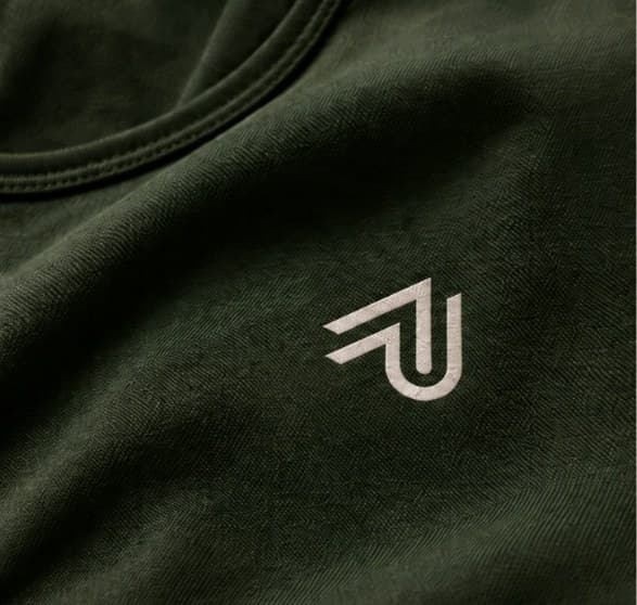 Detalle del logotipo de Aptinta bordado en una camiseta verde